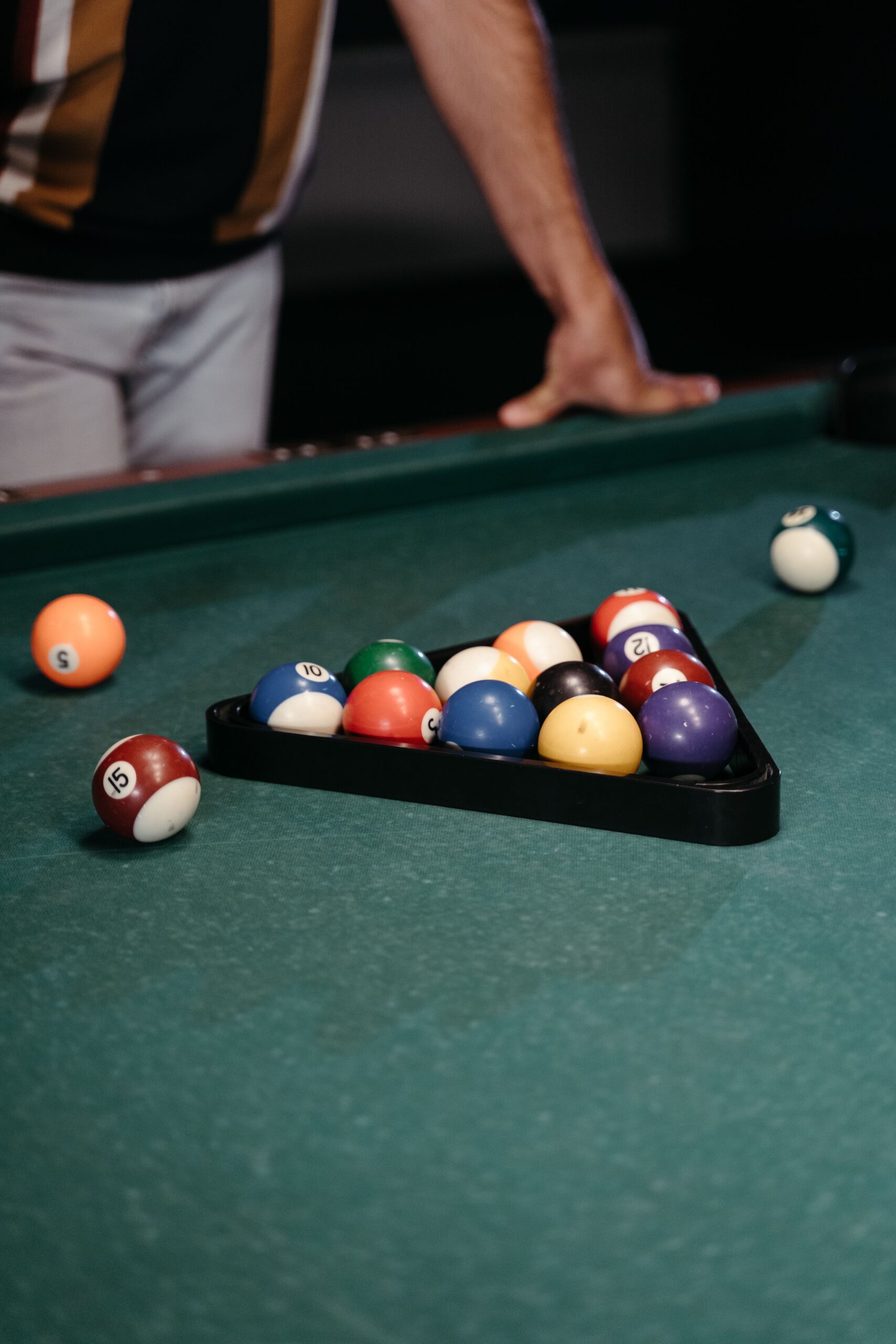Billiard balls arranged in a triangle rack on a green pool table before gameplay